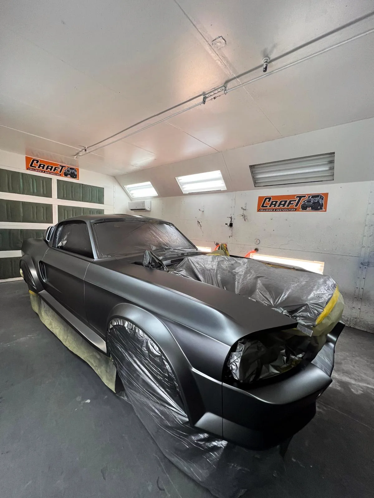 Custom Mustang fastback in matte grey with dark stripes inside the paint booth
