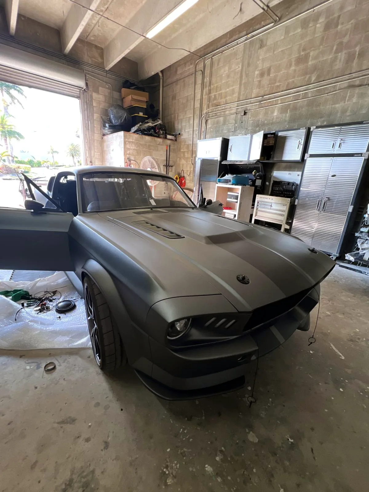 Custom matte grey Mustang fastback build parked inside the Craft Collision shop